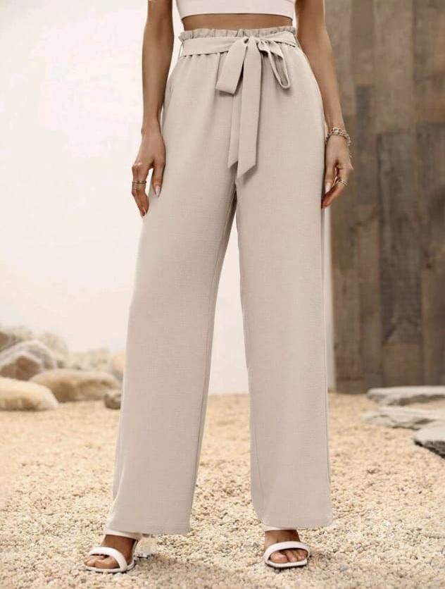 Pantalón de corte ancho en color beis claro con cintura alta con diseño "paperbag" fruncido, un cinturón de lazo ajustable de la misma tela y caída fluida